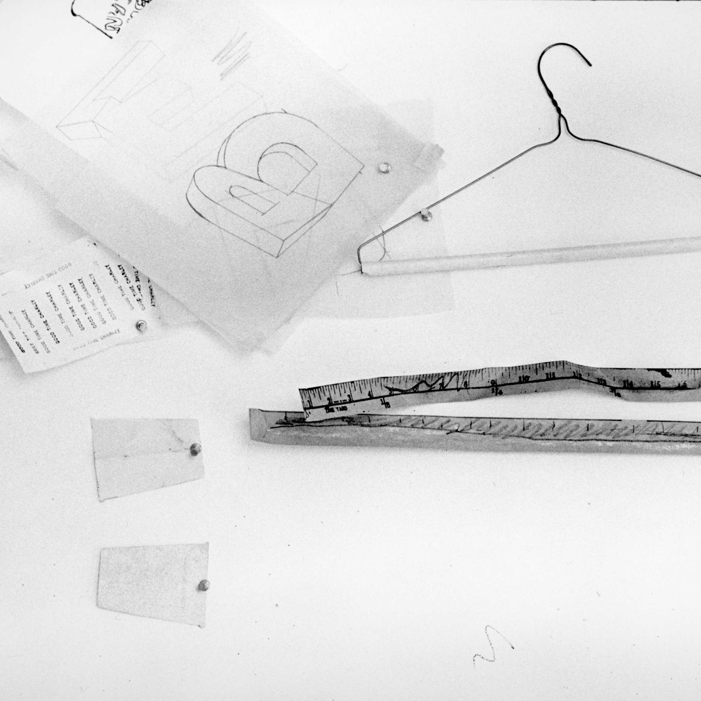 A coat hanger and some fragments of sketches for artworks pinned to a cork board