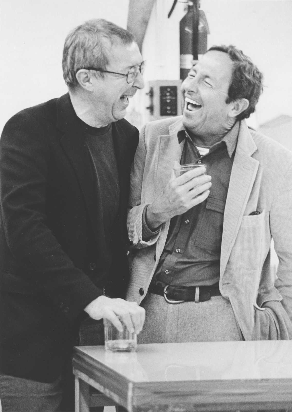 Two men standing close to each other and laughing together